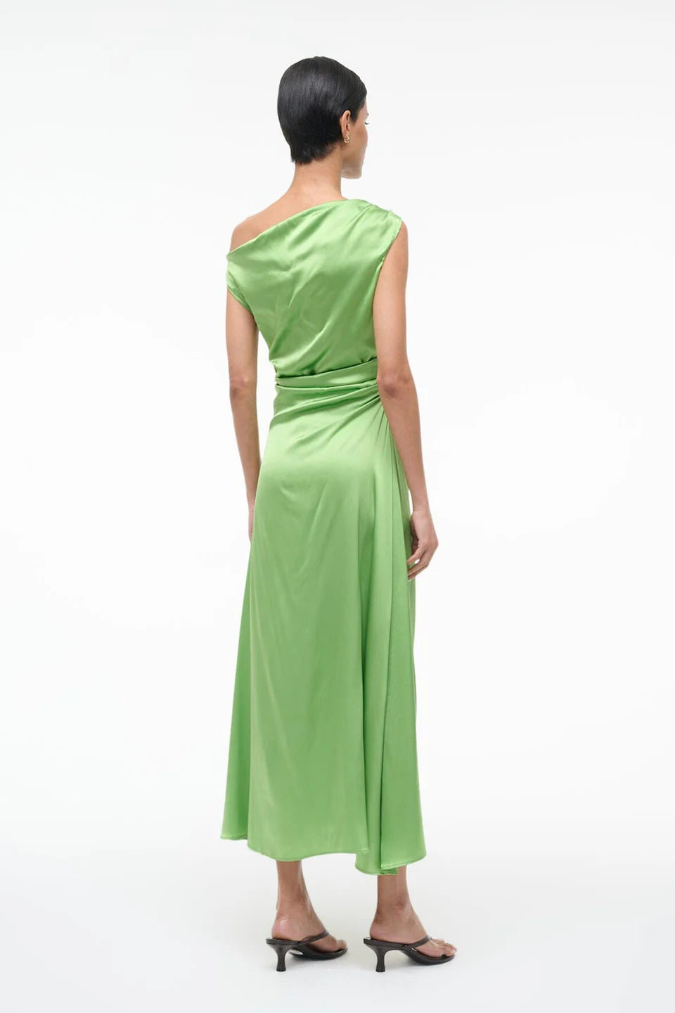 Woman wearing a green one-shoulder dress on a white background