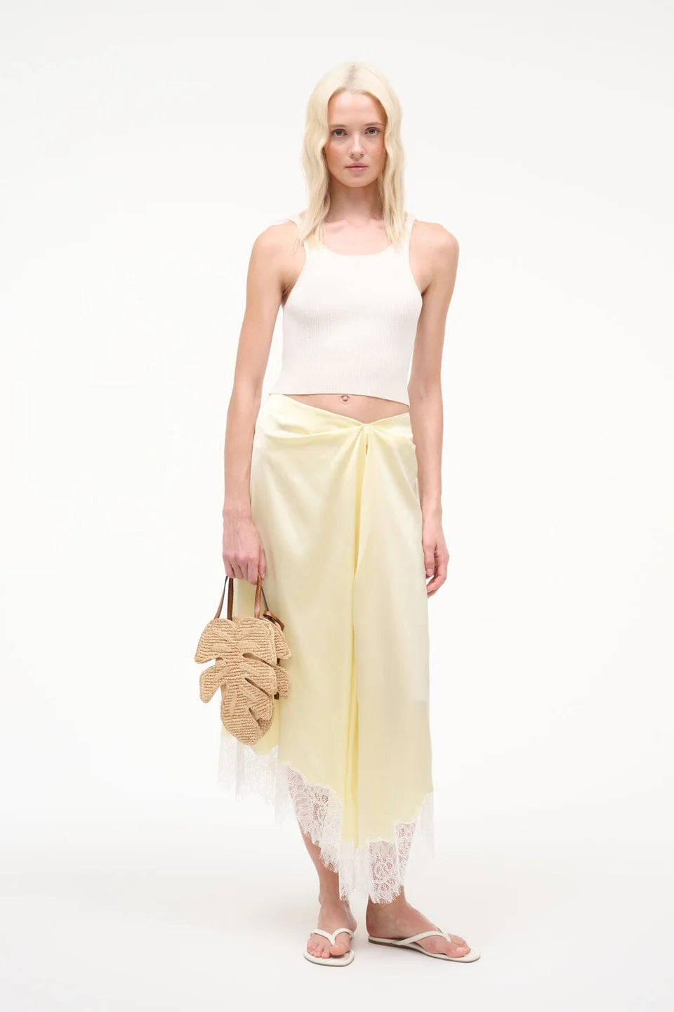Woman wearing a white top and yellow skirt with a white background
