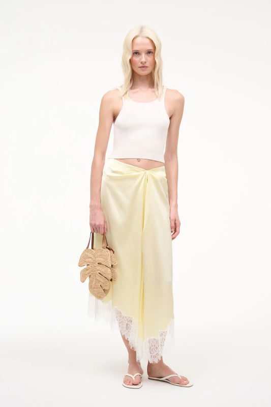 Woman wearing a white top and yellow skirt with a white background