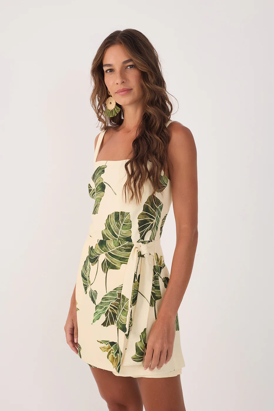Woman wearing a dress with tropical leaf pattern on a white background