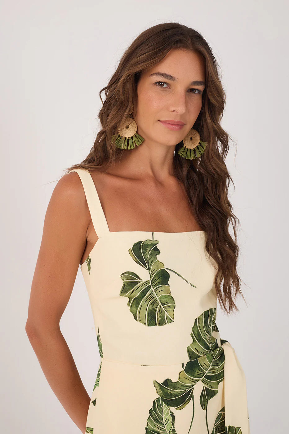 Woman wearing a dress with green leaf patterns on a plain background