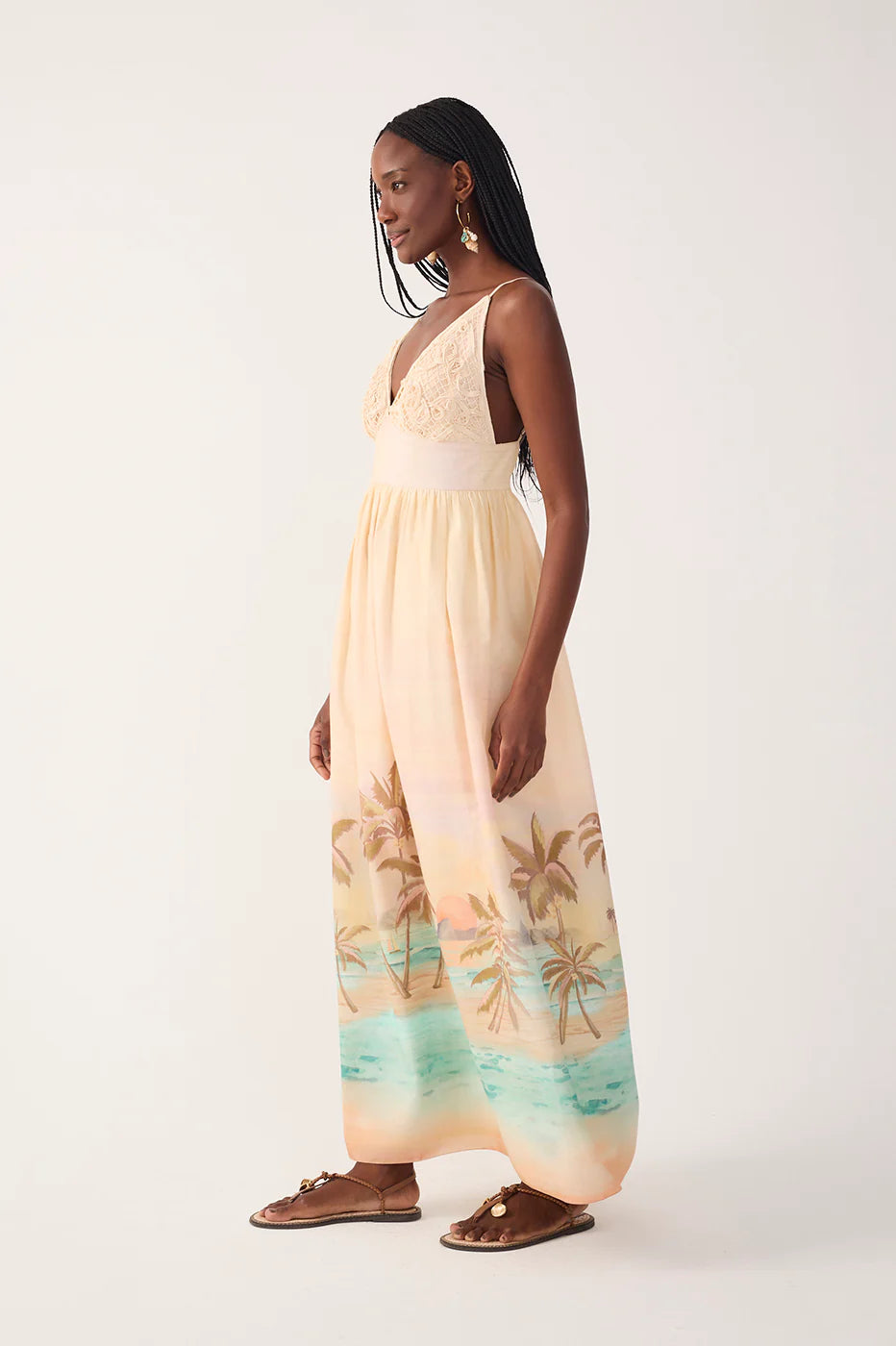 Woman wearing a beige dress with palm tree pattern on a white background