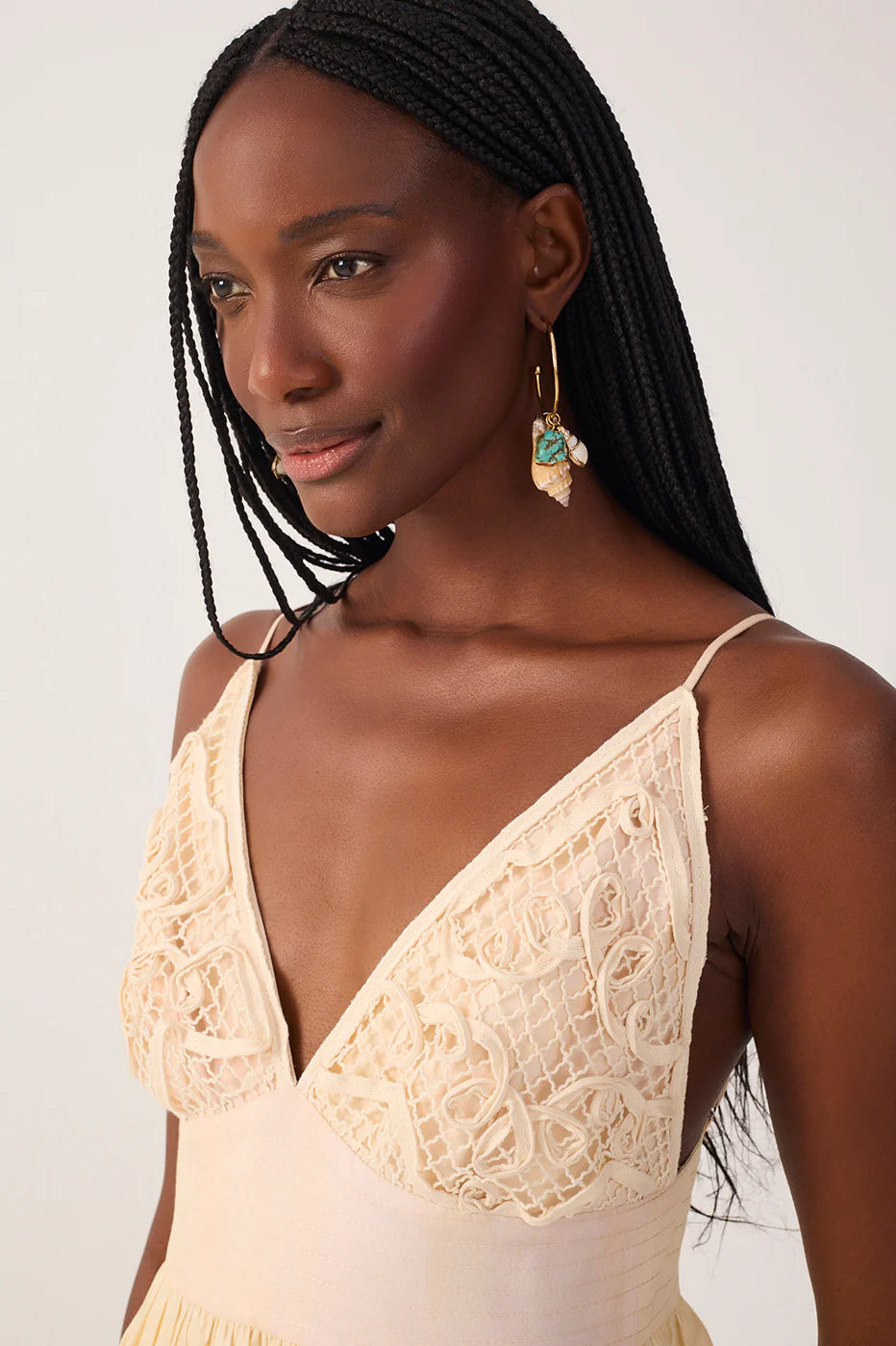 Woman wearing a beige lace top against a plain background