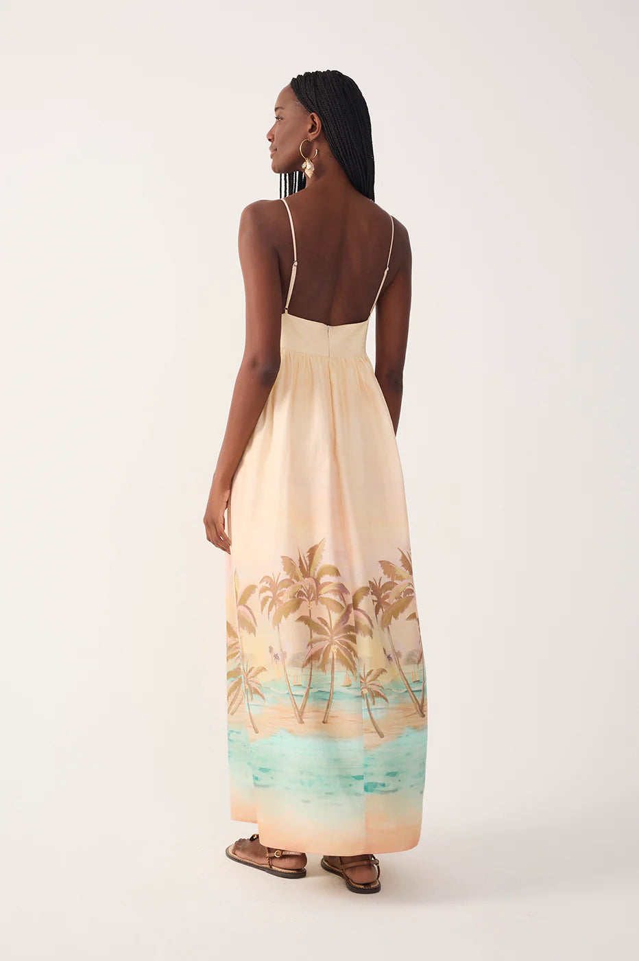 Woman wearing a long dress with palm tree design on a white background