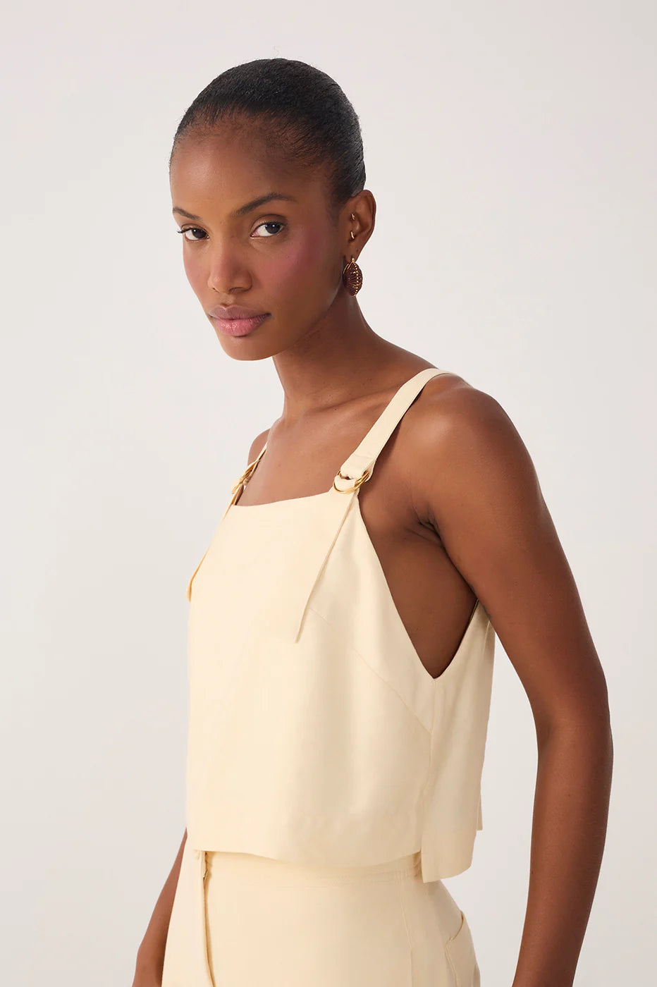 Woman wearing a beige sleeveless top against a white background