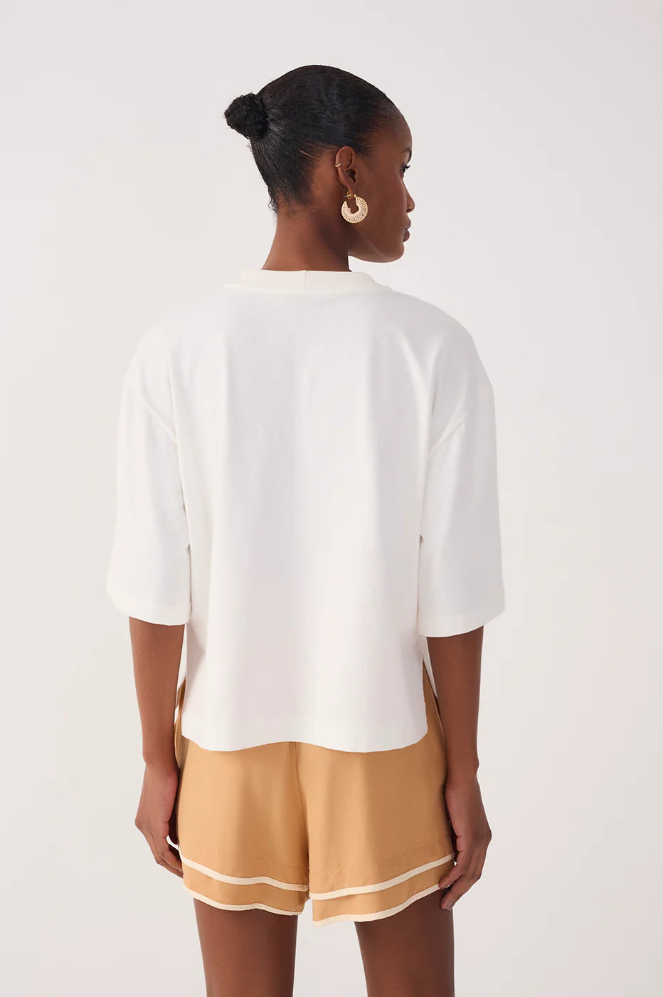 Woman wearing a white top and beige shorts on a white background