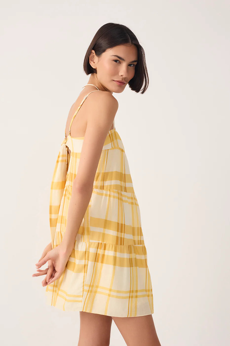 Woman wearing a yellow plaid dress against a white background