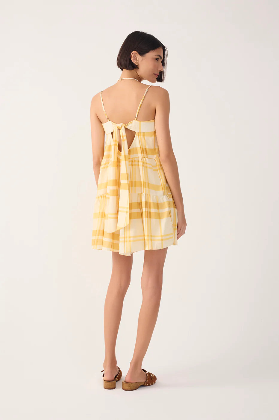 Woman wearing a yellow plaid dress on a white background