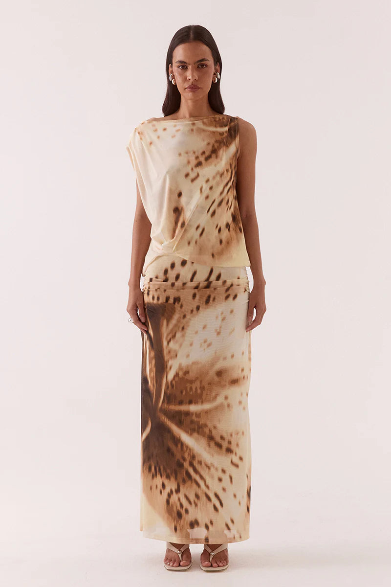 Woman wearing a sleeveless top and long skirt with a brown abstract pattern on a white background