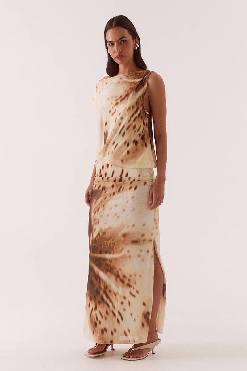 Woman wearing a long, patterned dress on a plain background