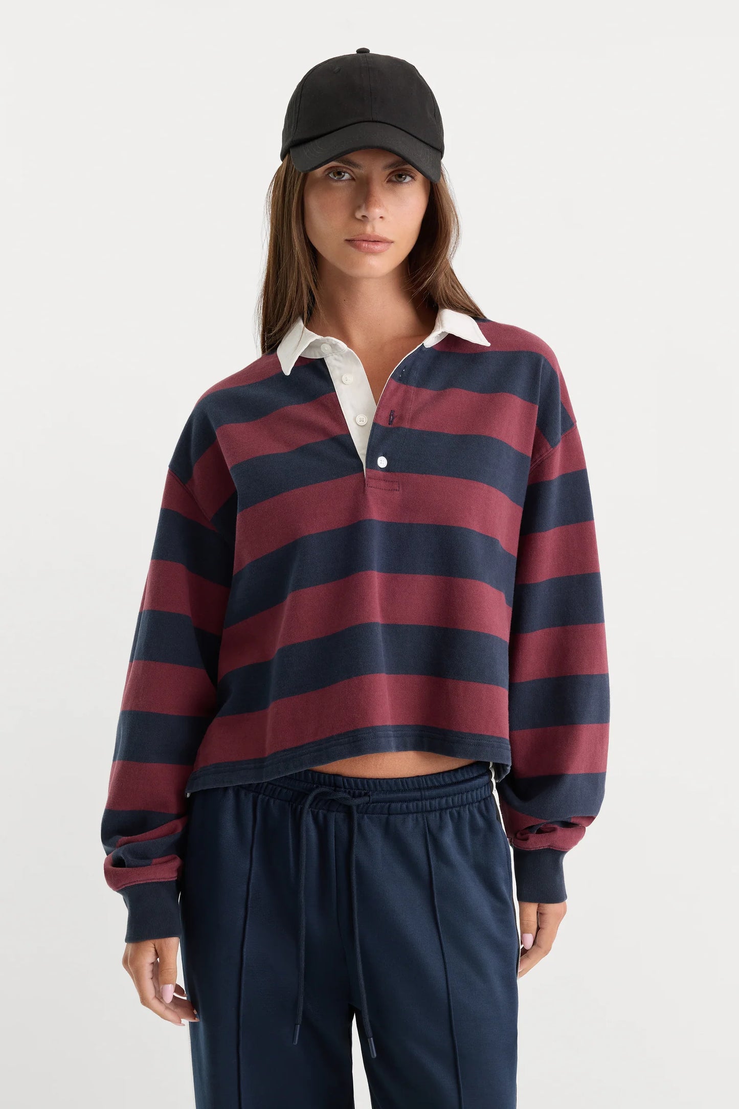 Person wearing a striped rugby shirt and dark pants on a white background