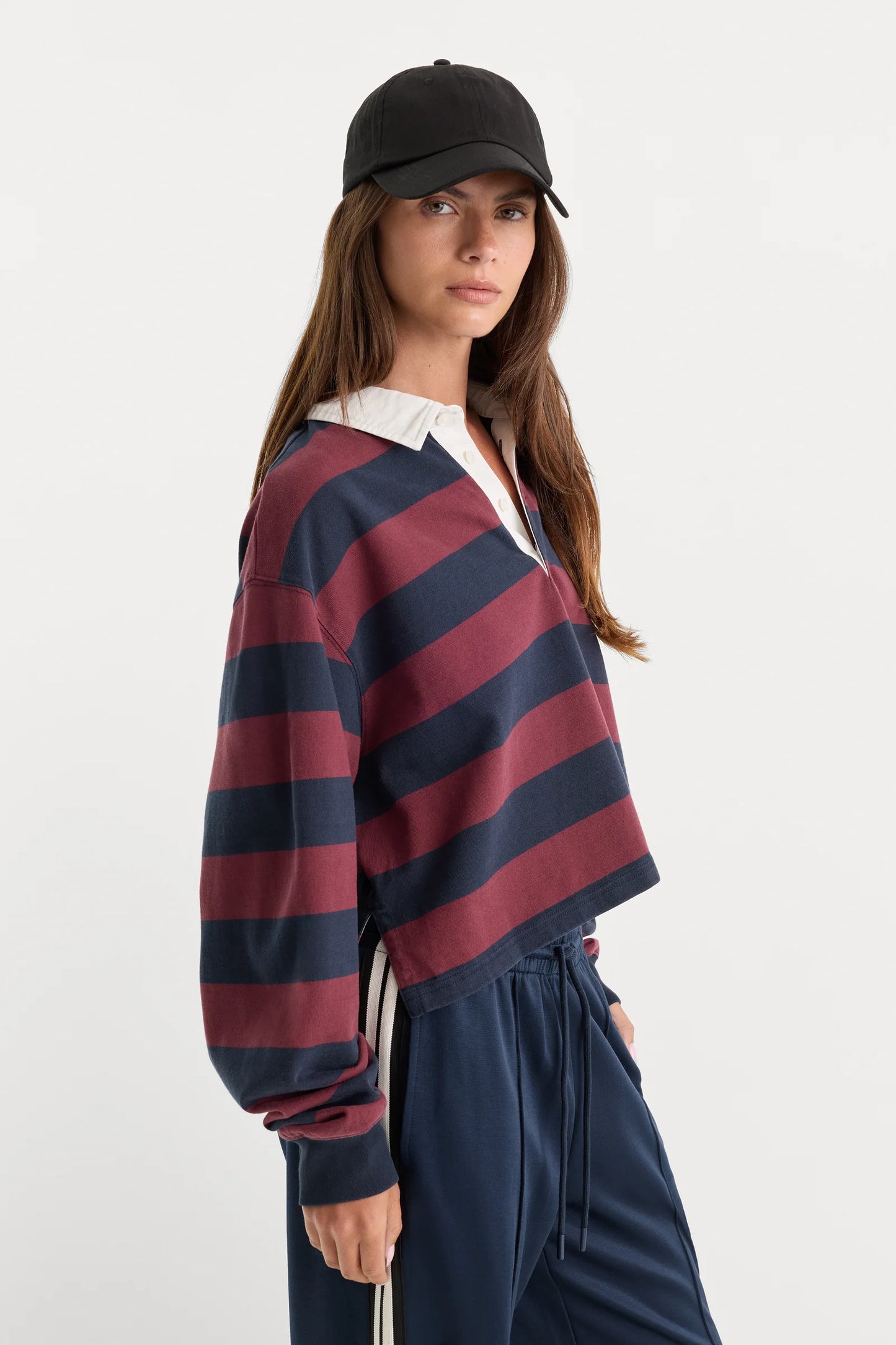 Woman wearing a red and navy striped shirt with a black cap on a white background