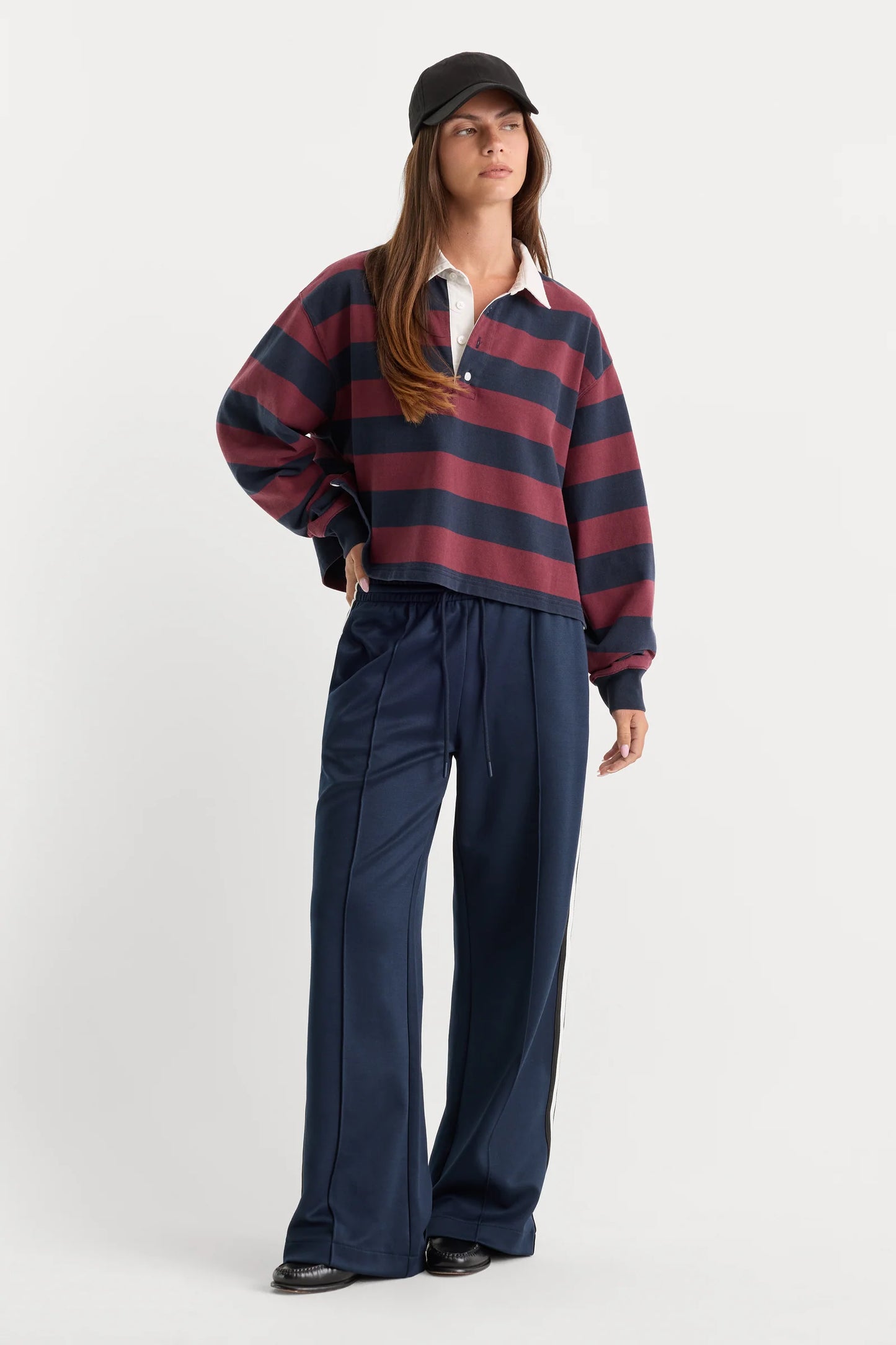 Person wearing a red and blue striped sweater with navy pants on a white background