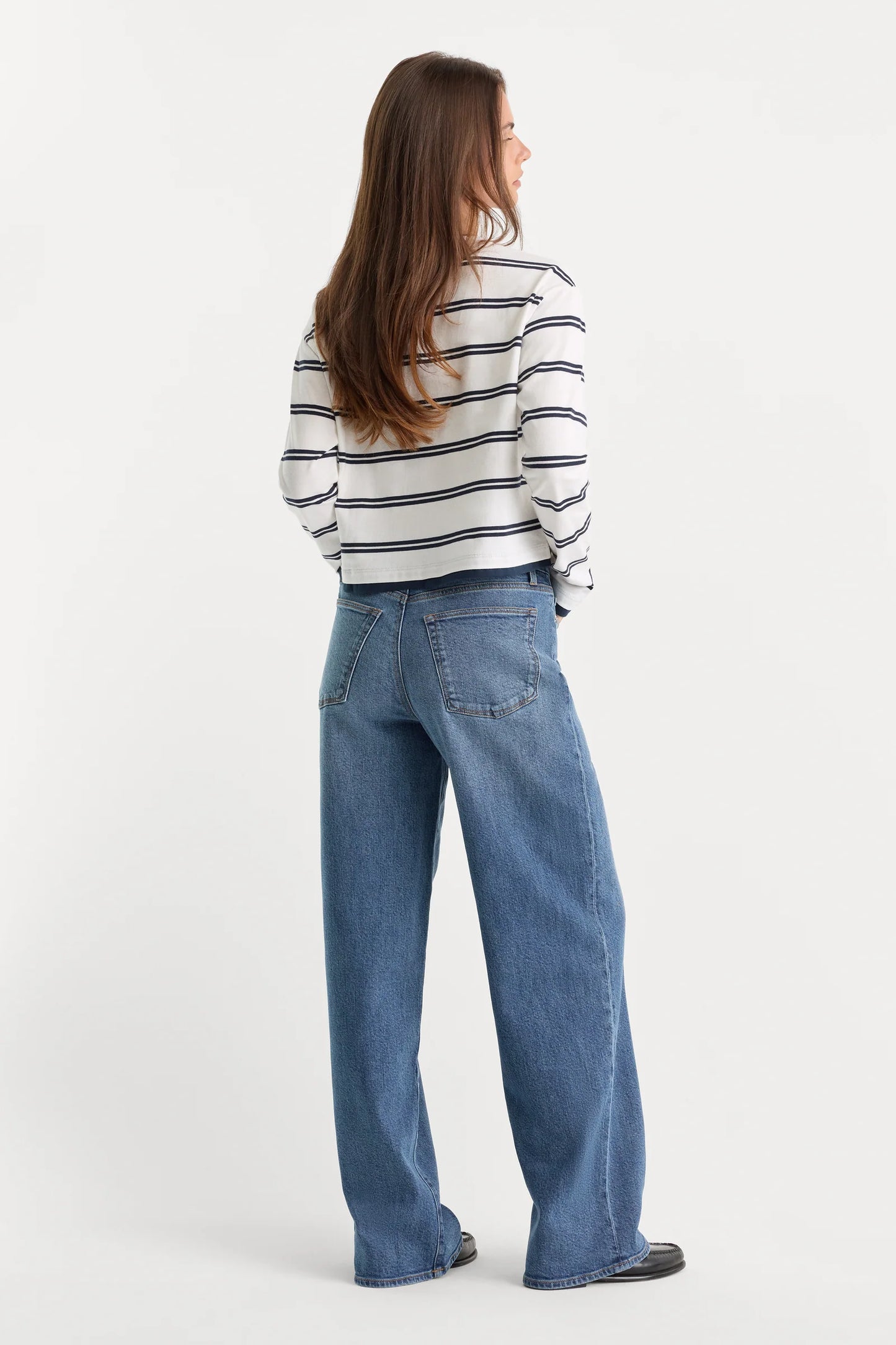 Person wearing a striped shirt and blue jeans on a white background