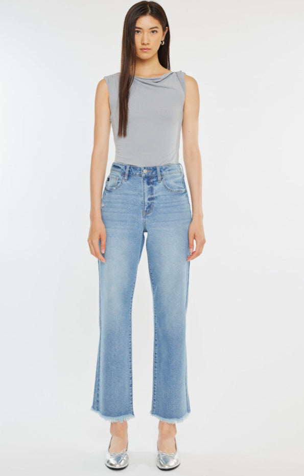 Woman wearing a light gray sleeveless top and blue jeans With a frayed bottom on a white background
