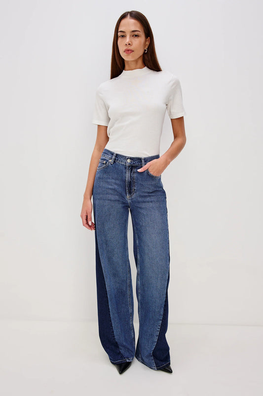Woman wearing a white top and blue flared jeans on a white background