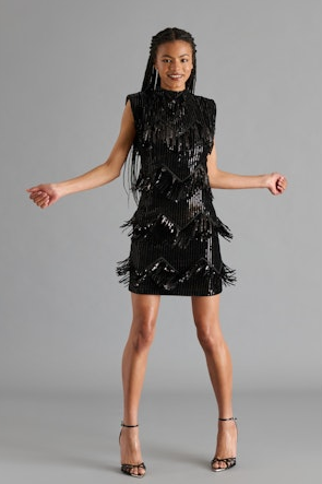Woman wearing a black sequin dress against a gray background