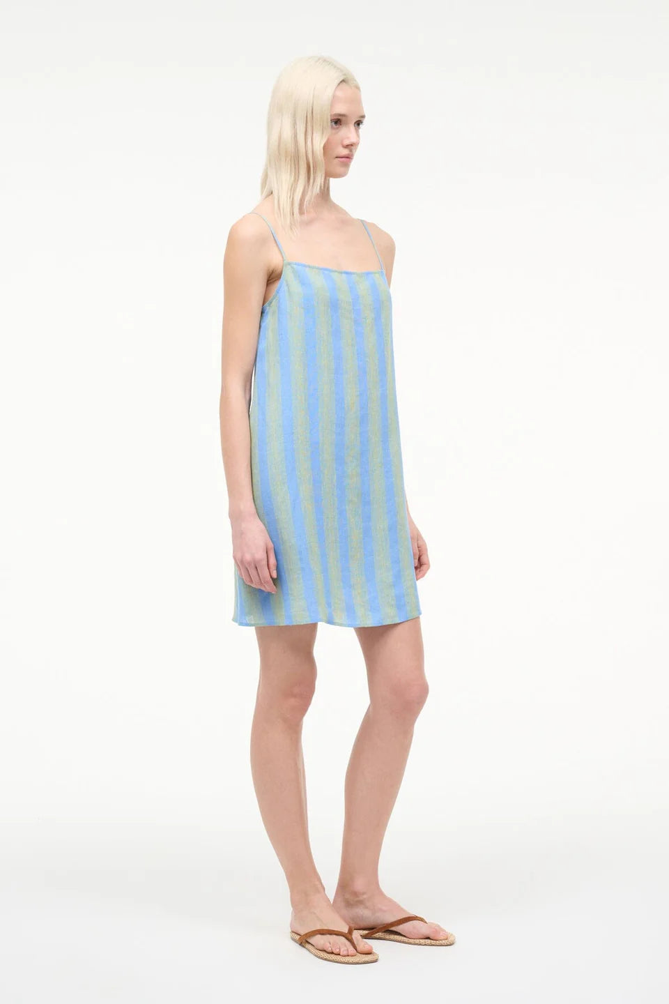 Woman wearing a light blue and white striped dress on a white background