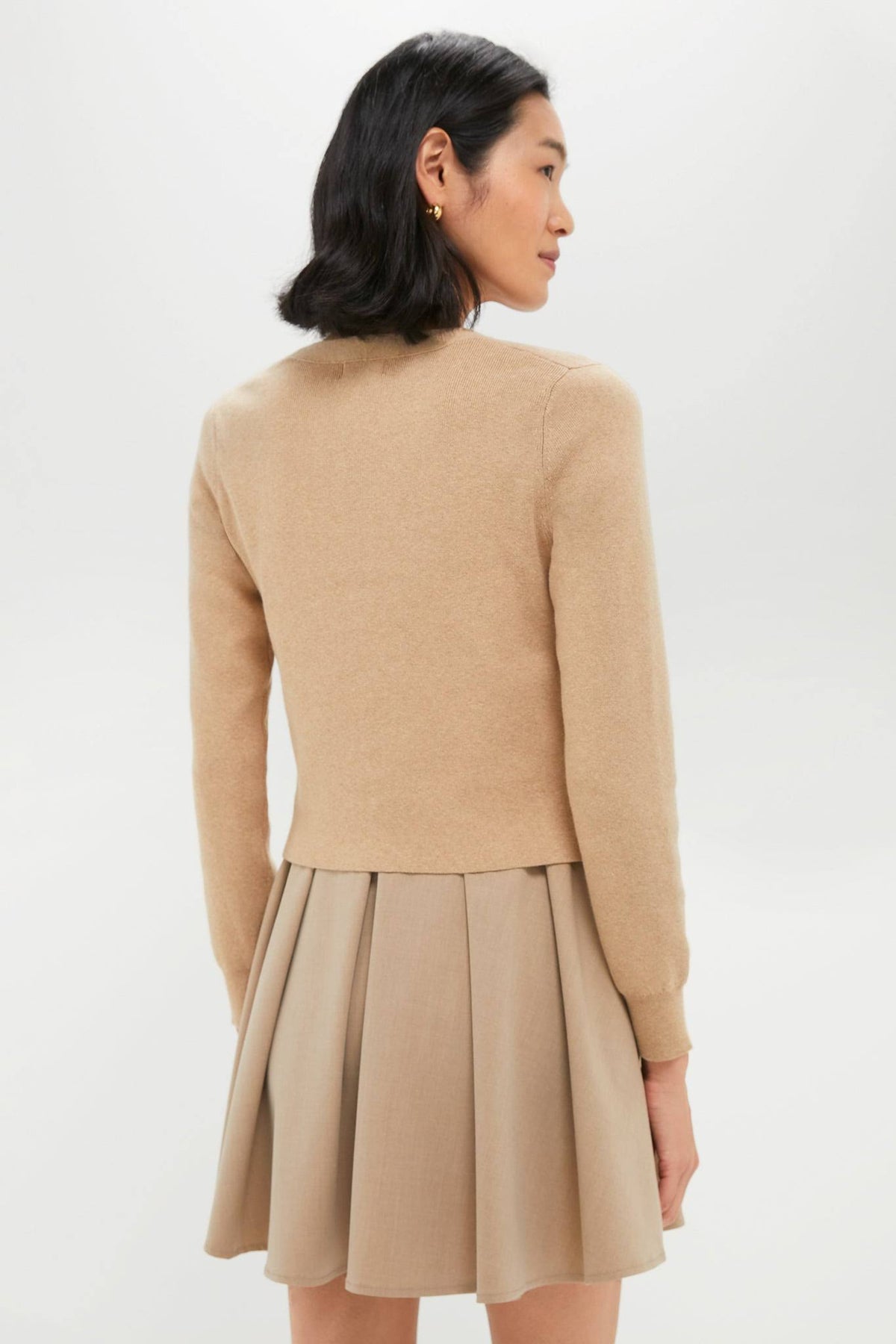 Woman wearing a beige sweater and skirt set on a white background