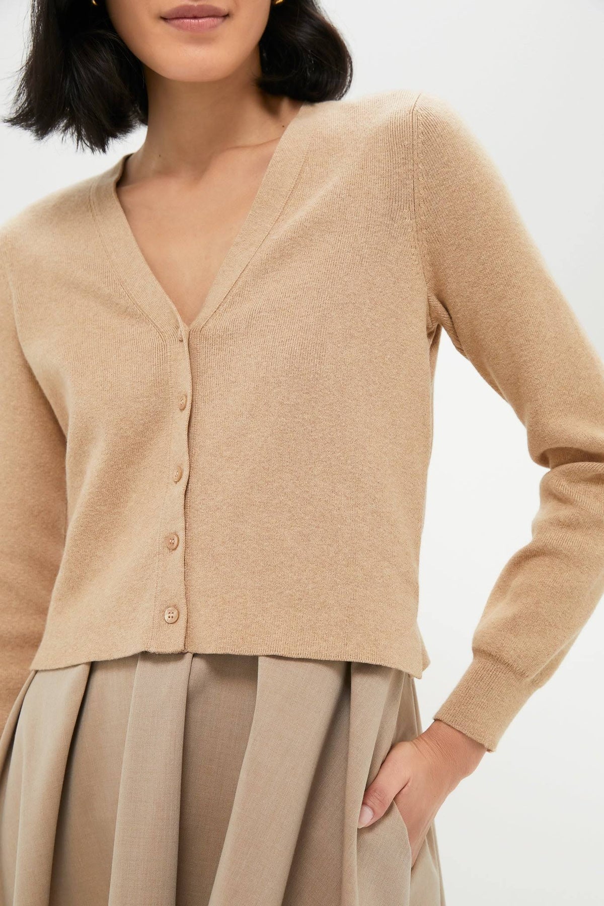Woman wearing a beige cardigan and skirt on a white background