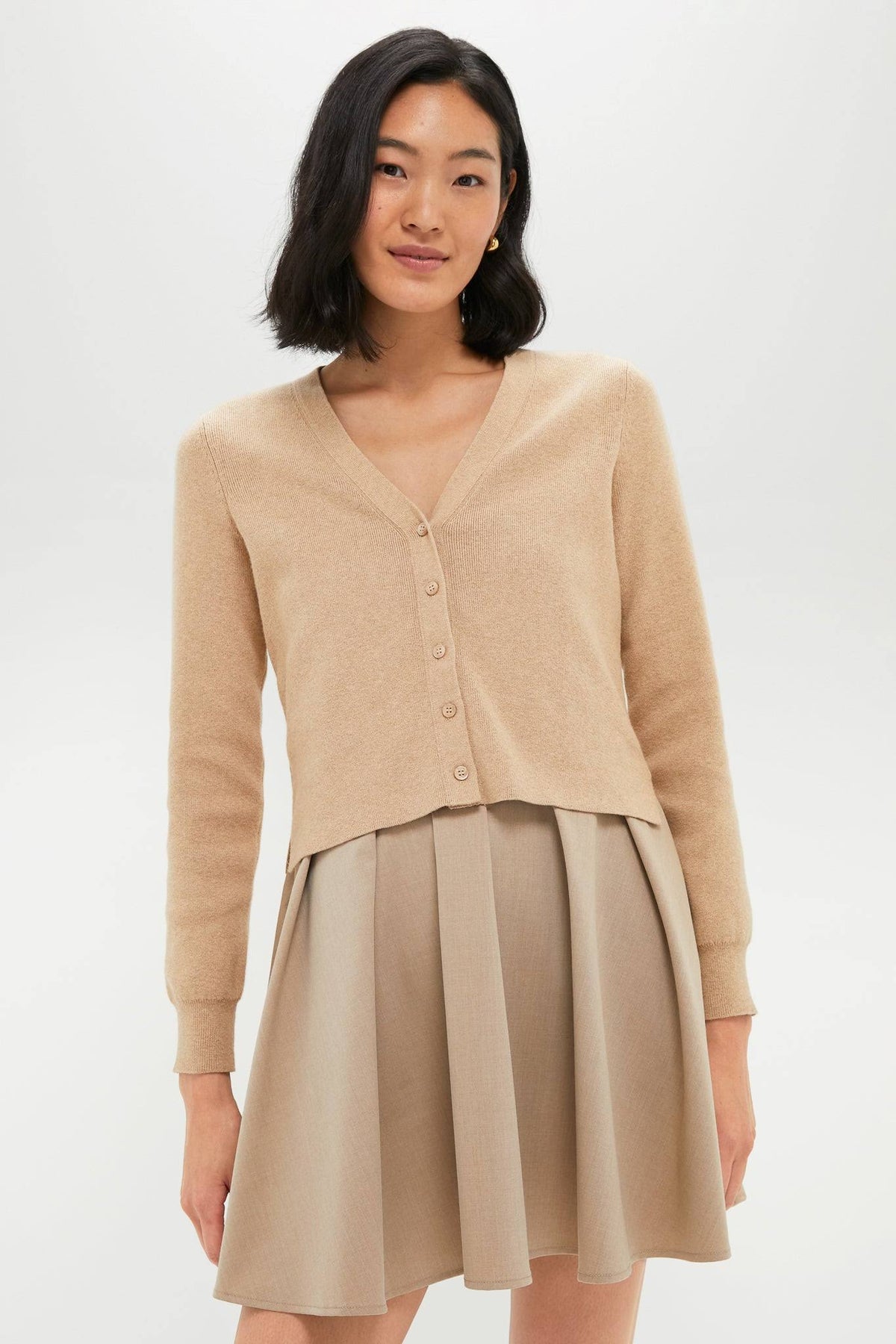 Woman wearing a beige cardigan and dress on a white background
