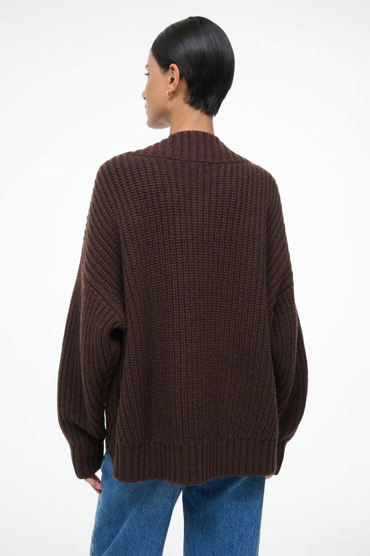 Person wearing a brown knitted cardigan on a white background