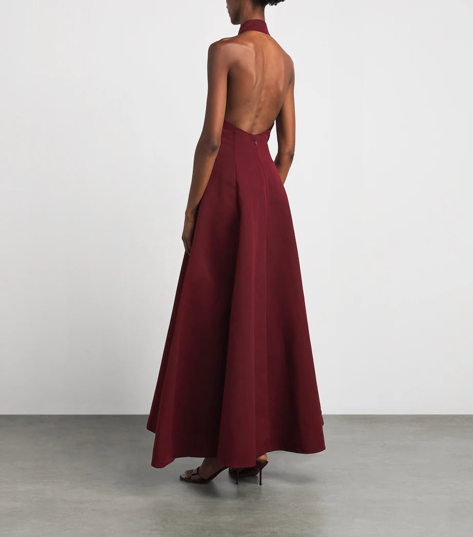 A model wearing the Staud Carmino Stella dress from the back view showcasing the ow back and halter neck style.