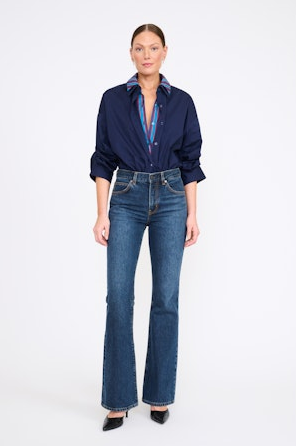 Woman wearing a navy shirt and blue jeans on a white background