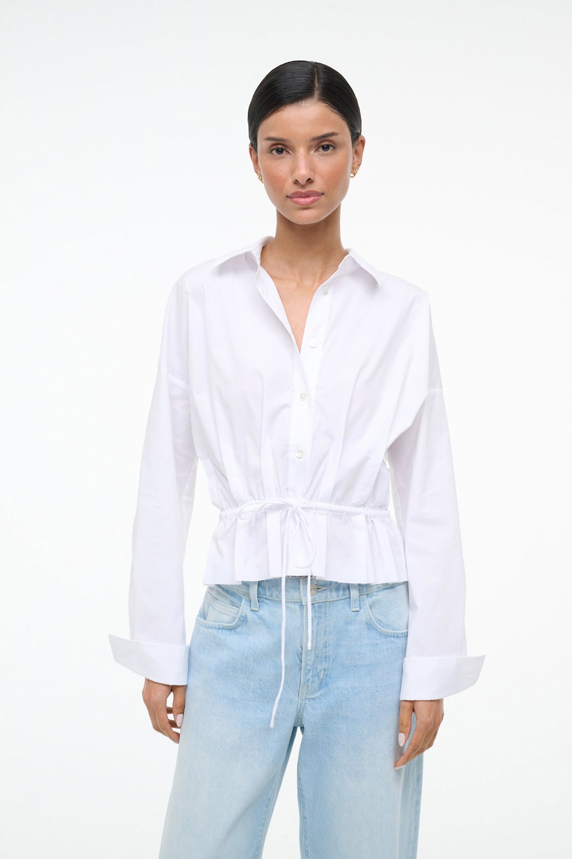 Woman wearing a white shirt and light blue jeans on a white background