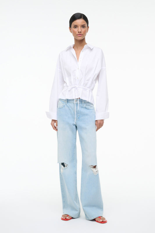 Woman wearing a white blouse and light blue jeans on a white background