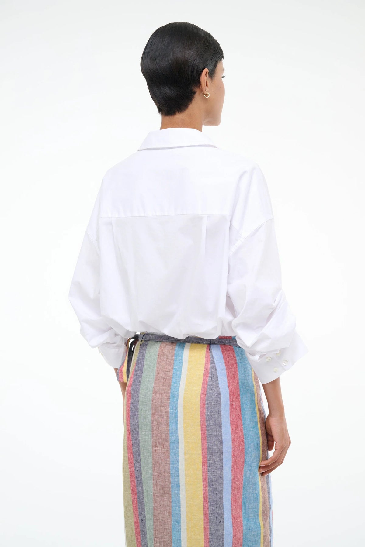 Woman wearing a white shirt and colorful striped skirt on a white background