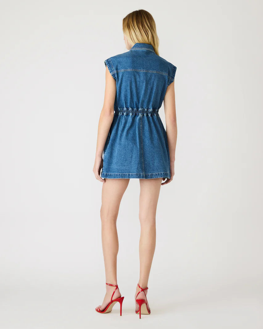Woman wearing a sleeveless blue denim mini dress on a white background