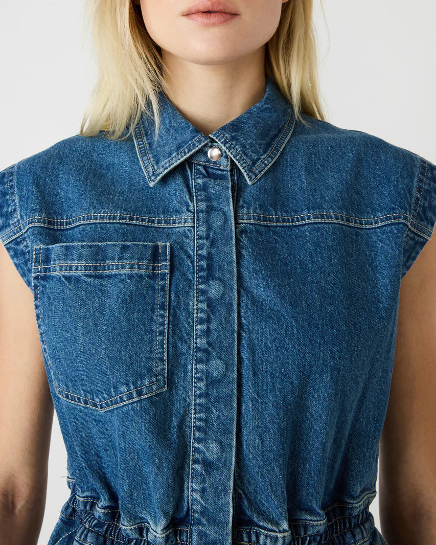 Blue denim sleeveless dress worn by a person on a plain background