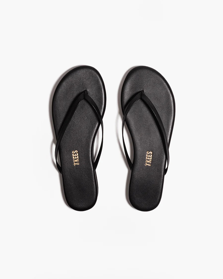 Black flip-flops with 'TIKES' branding on a white background from the top view