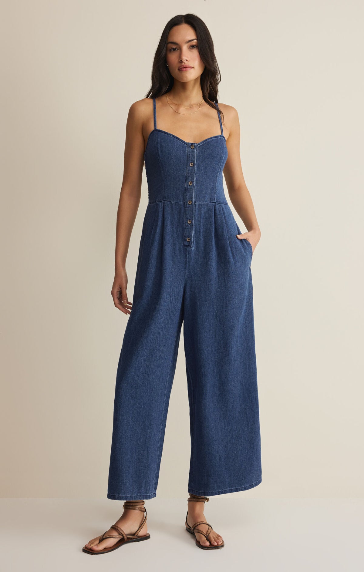 Woman wearing a blue jumpsuit on a beige background