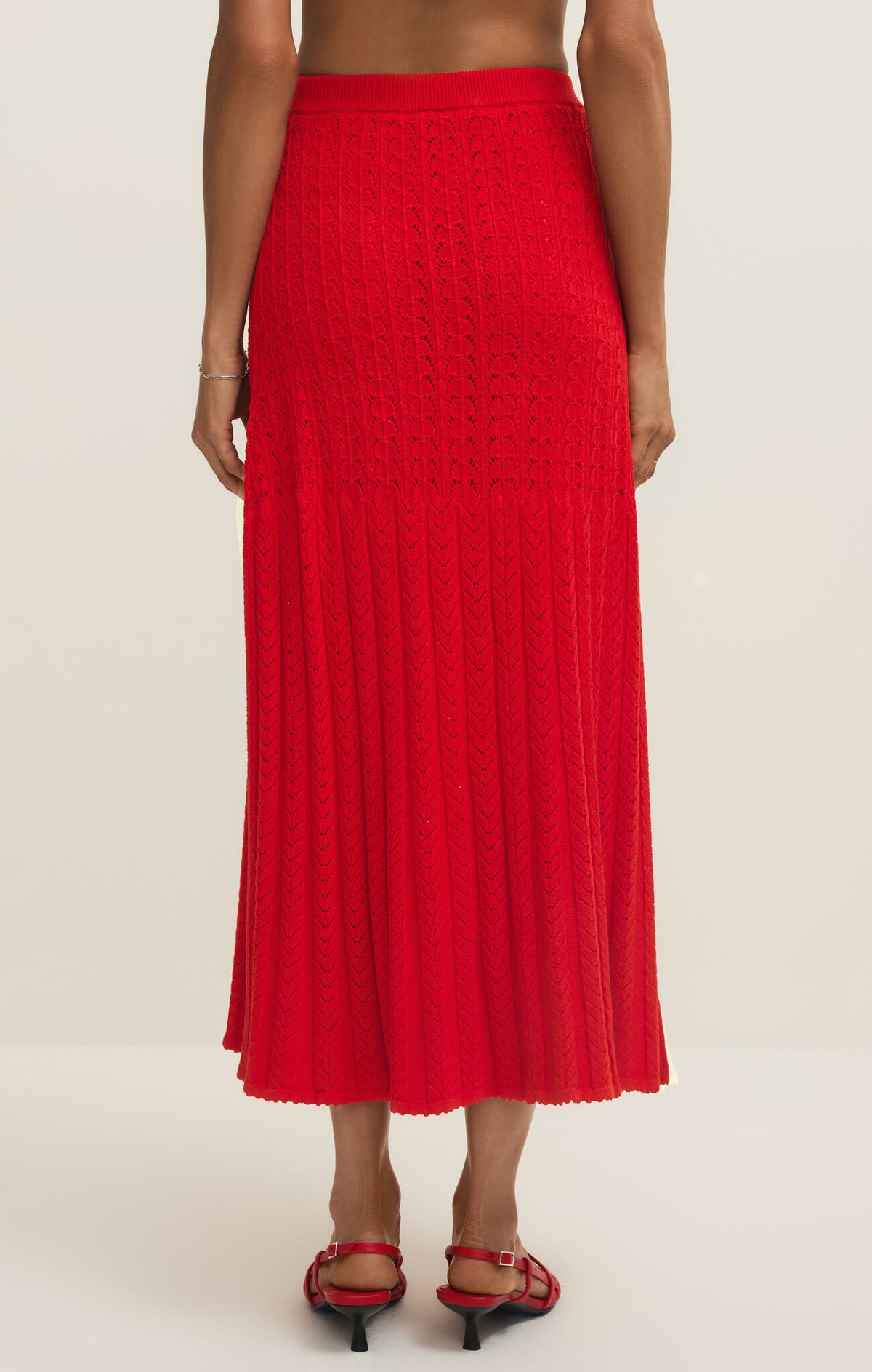 Red pleated midi sweater skirt worn by a person on a white background
