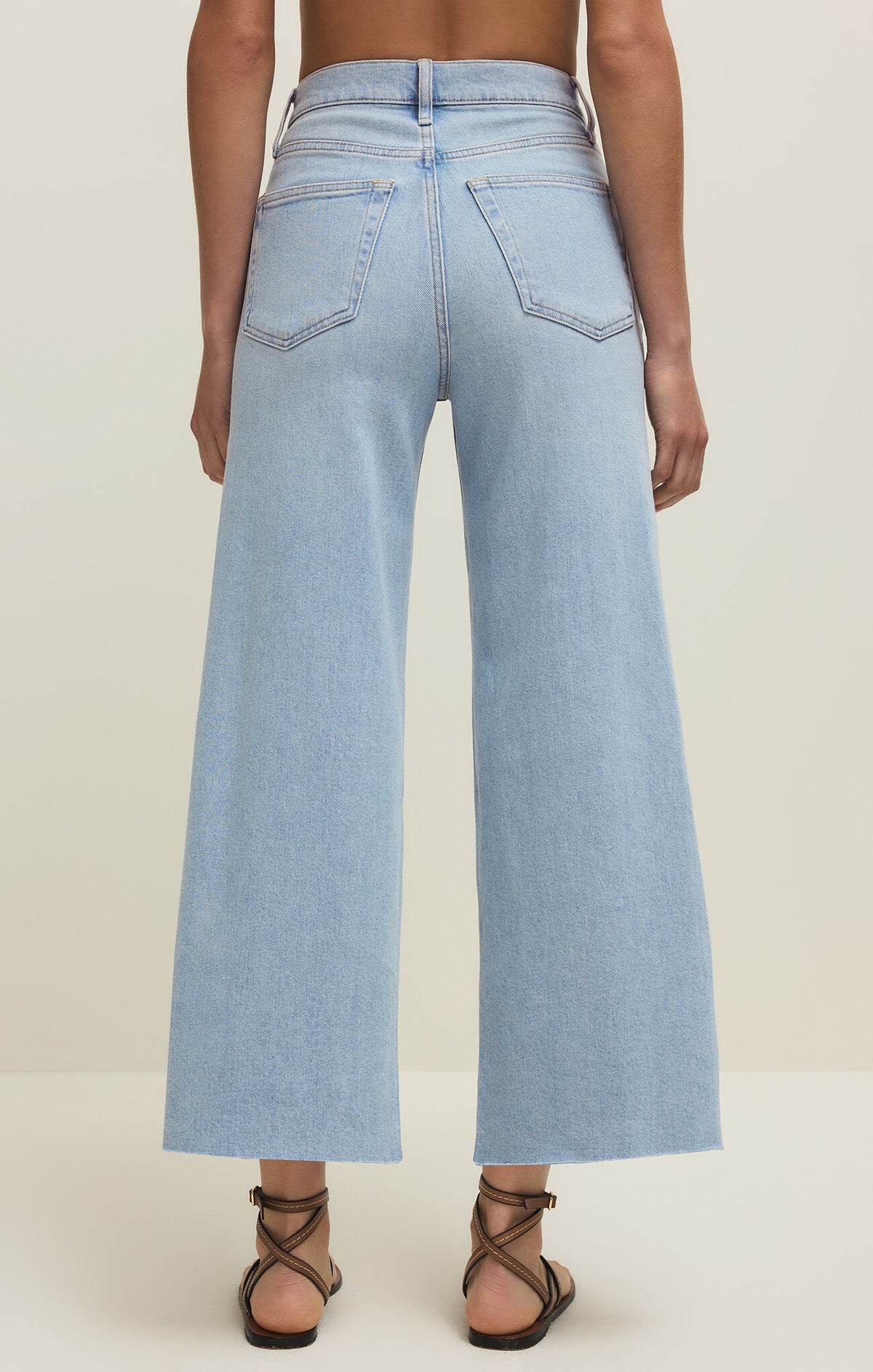 Light blue cropped jeans worn by a person on a plain background