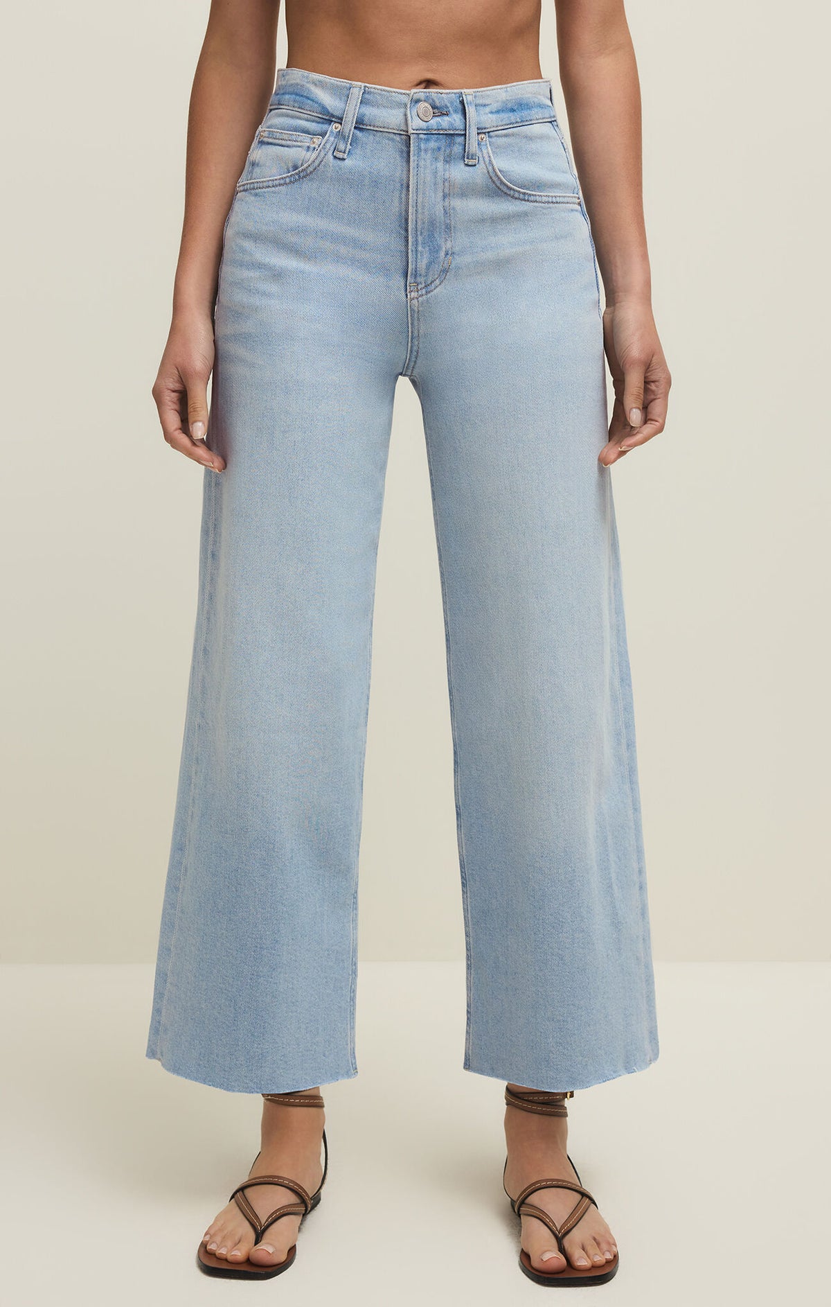 Light blue cropped jeans worn by a person on a plain background