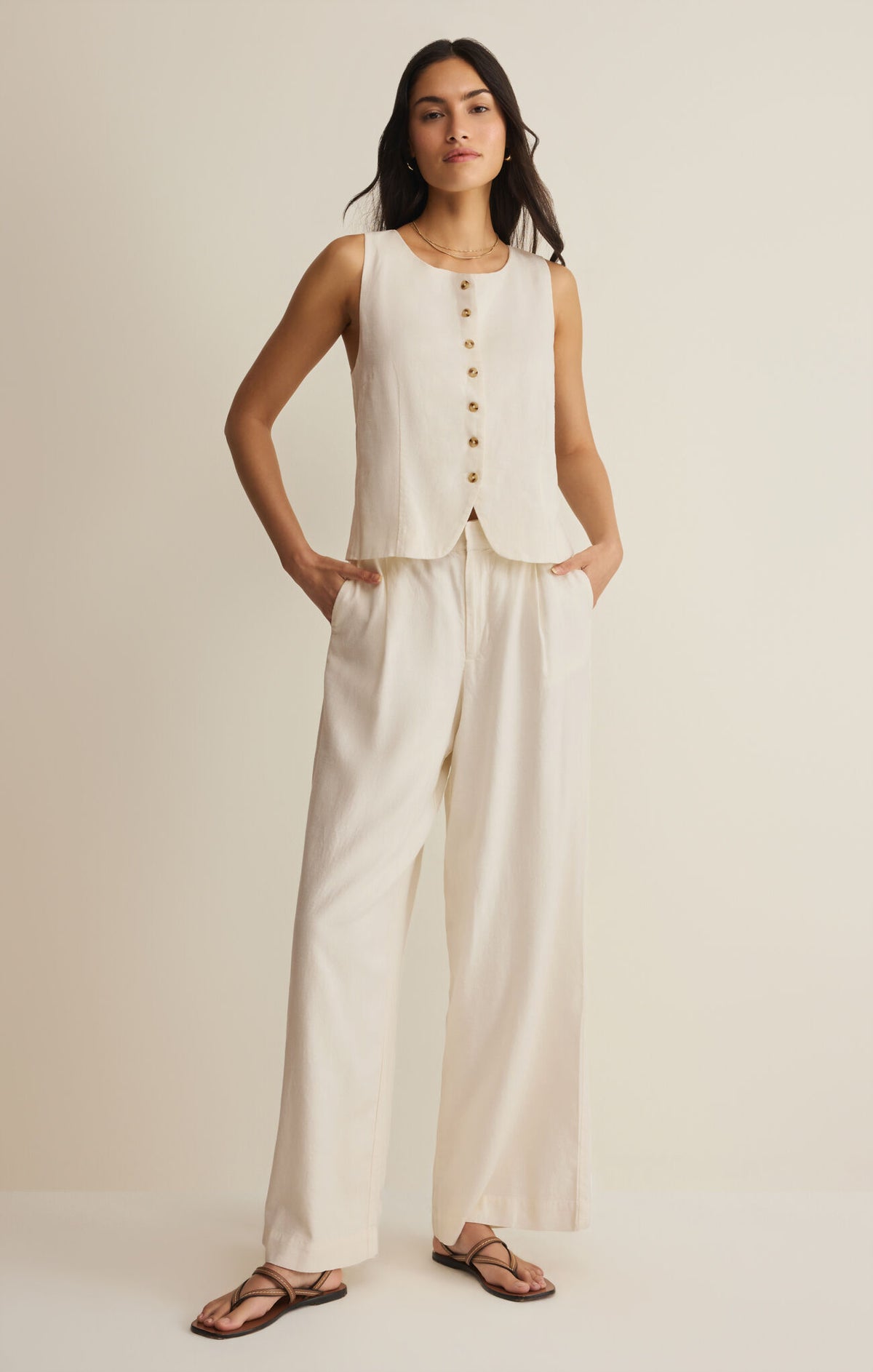 Woman wearing a sleeveless top and wide-leg pants on a plain background