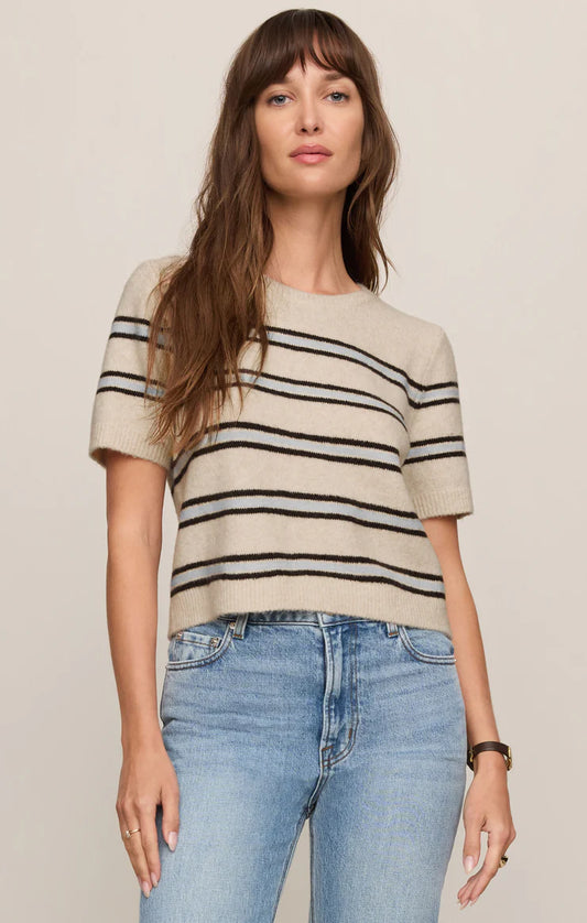 Woman wearing a striped sweater and jeans against a plain background