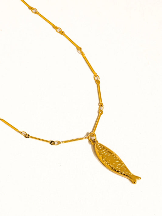 Close up of gold necklace with fish charm
