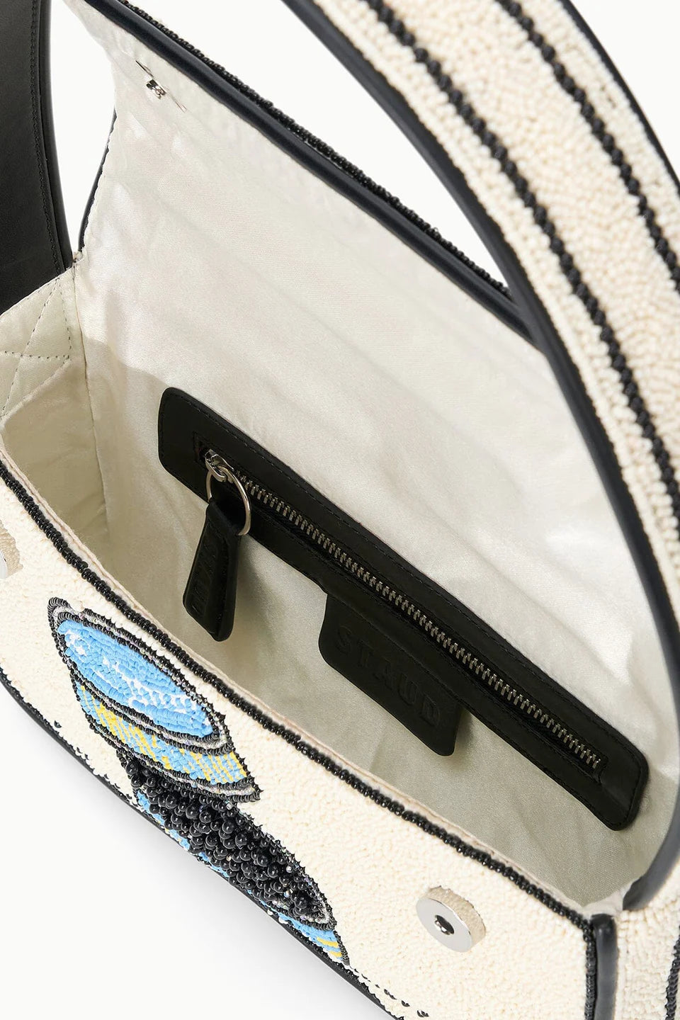 Close-up of a handbag with a decorative handle and embroidered design.