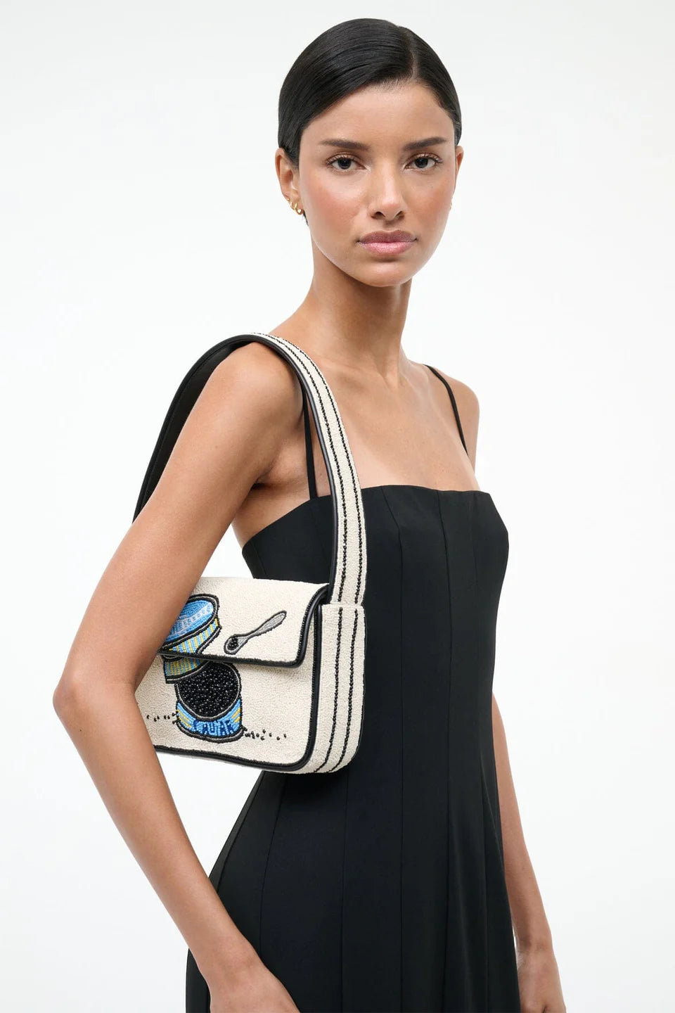 Woman carrying a white handbag with artistic design on a plain background