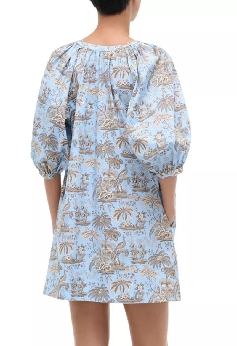 Light blue dress with beige pattern worn by a person on a white background